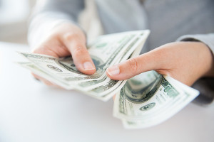 business, finance, saving, banking and people concept - close up of woman hands counting us dollar money