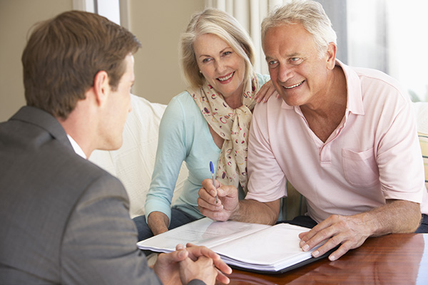 Attractive Baby Boomer couple reviewing paperwork with male realtor