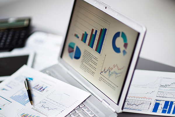 laptop and hard copy financial charts