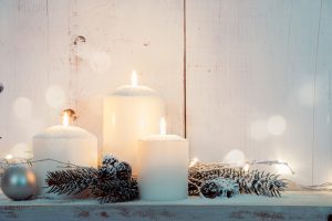 White pillar candles surrounded by snow covered pinecones